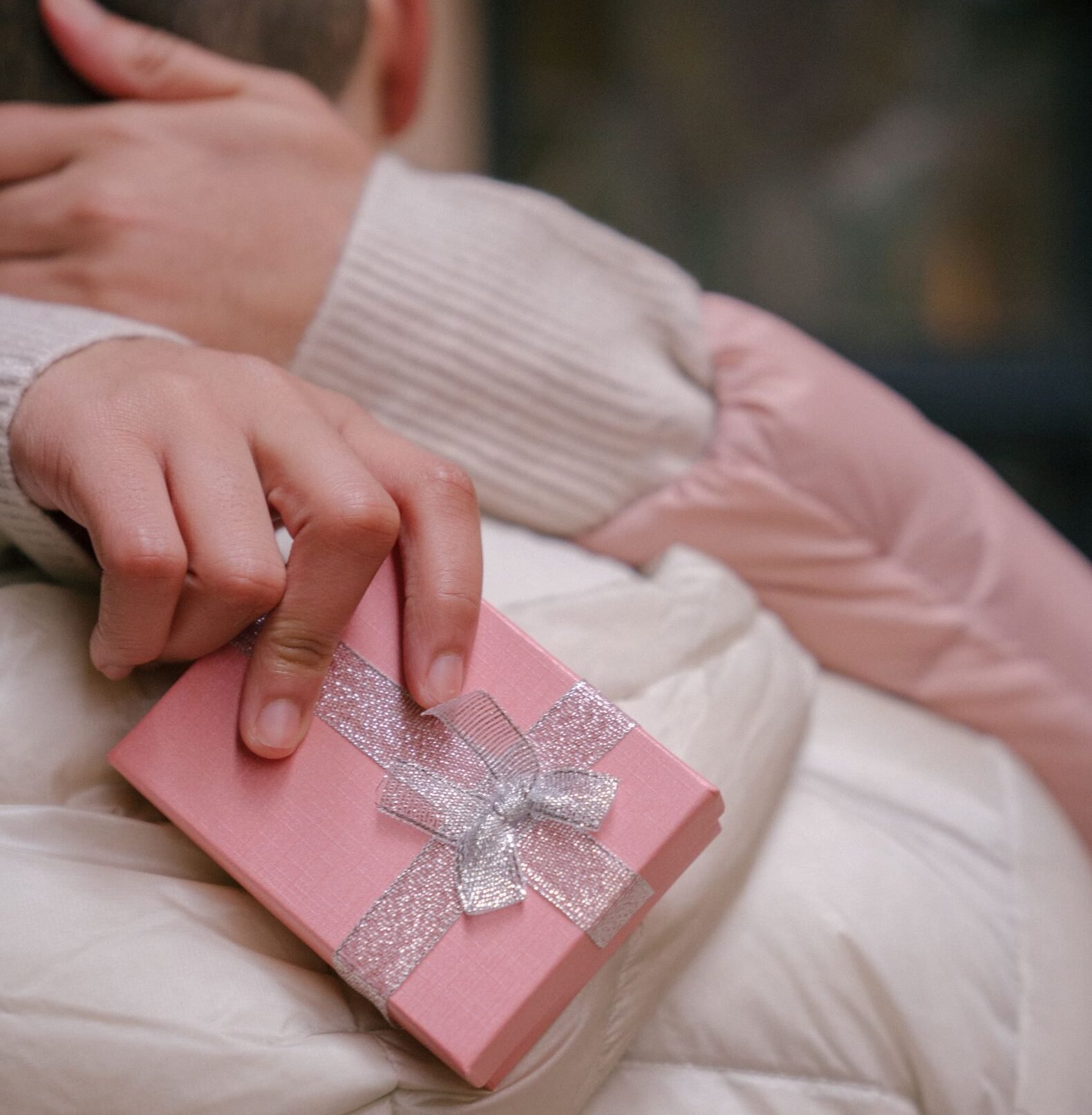 Unrecognizable woman in casual clothes holding present in hand and embracing anonymous boyfriend in daylight
